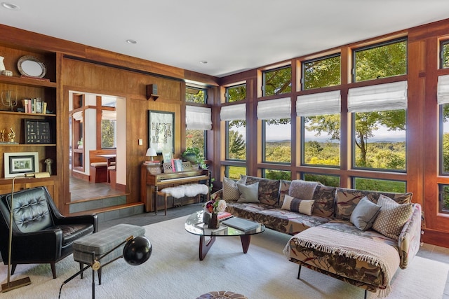 living area featuring built in features, carpet, and wood walls