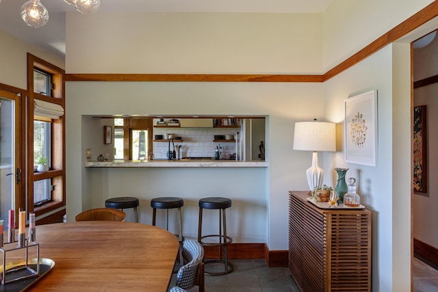 tiled dining space featuring baseboards and bar
