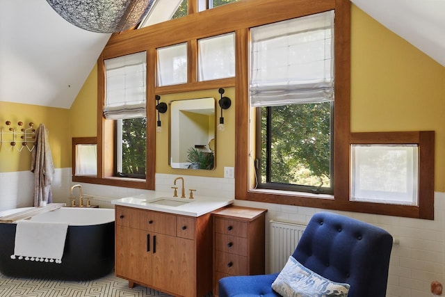 bathroom with a freestanding bath, radiator heating unit, lofted ceiling, wainscoting, and tile walls