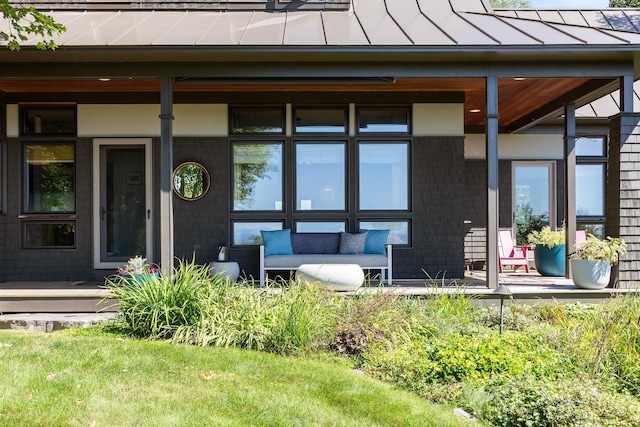 property entrance featuring an outdoor living space, metal roof, a porch, and a standing seam roof
