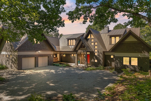view of front of property featuring brick siding, an attached garage, metal roof, and a standing seam roof