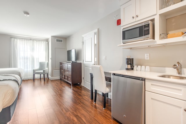 kitchen featuring visible vents, dark wood-style flooring, a sink, stainless steel appliances, and light countertops