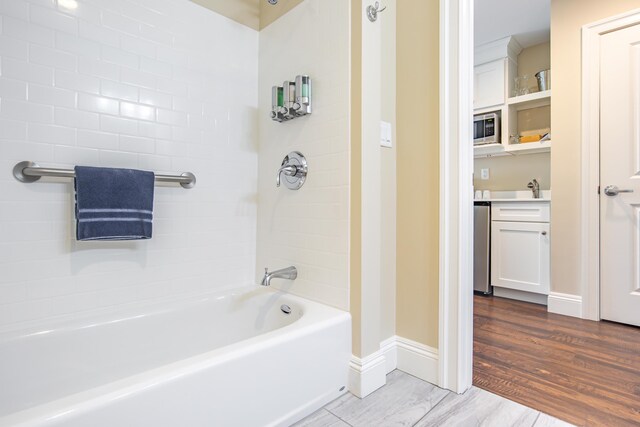 full bath featuring vanity, wood finished floors, tub / shower combination, and baseboards