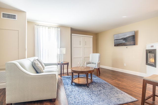 living area featuring visible vents, baseboards, and dark wood-style flooring