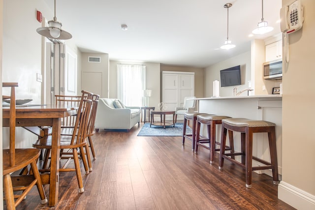 dining area featuring dark wood finished floors, visible vents, and baseboards