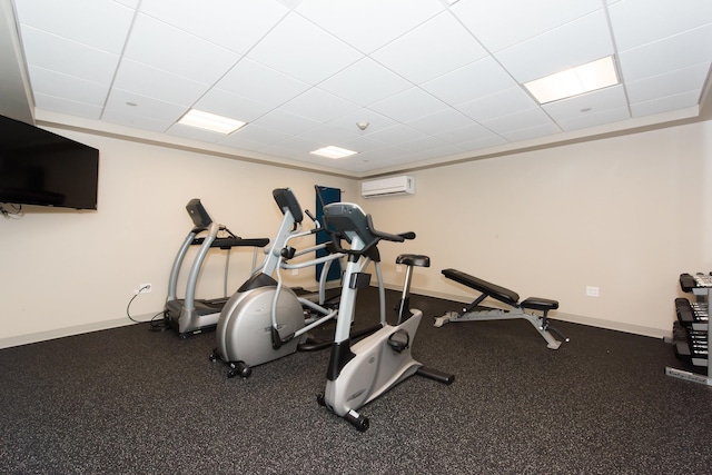 workout room with a drop ceiling, baseboards, and an AC wall unit