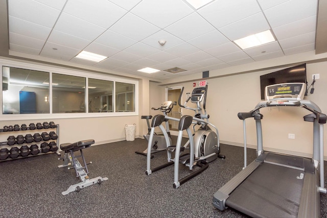 gym with a paneled ceiling and baseboards