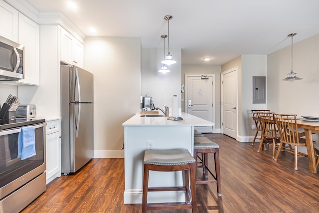 kitchen featuring dark wood finished floors, a kitchen breakfast bar, stainless steel appliances, white cabinetry, and a sink