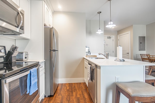 kitchen featuring dark wood finished floors, a breakfast bar, appliances with stainless steel finishes, a peninsula, and a sink