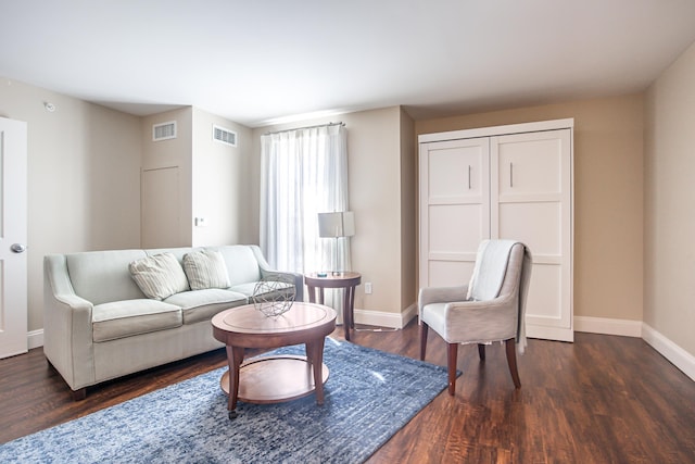 living room with dark wood finished floors, visible vents, and baseboards