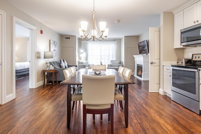 dining room with visible vents, a notable chandelier, a warm lit fireplace, baseboards, and dark wood-style flooring