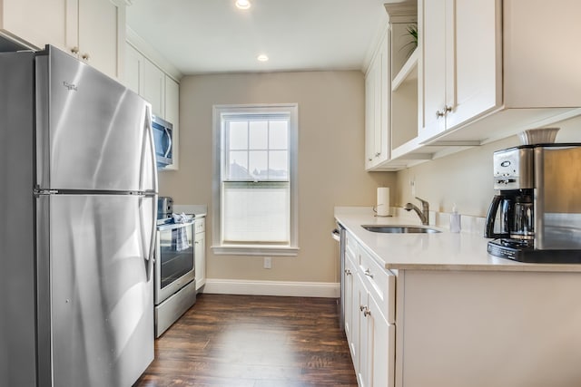 kitchen featuring baseboards, dark wood finished floors, light countertops, appliances with stainless steel finishes, and a sink