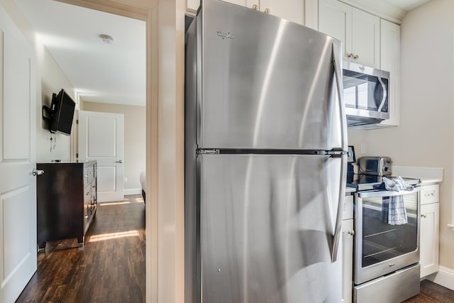 kitchen with baseboards, appliances with stainless steel finishes, white cabinets, and dark wood-style flooring