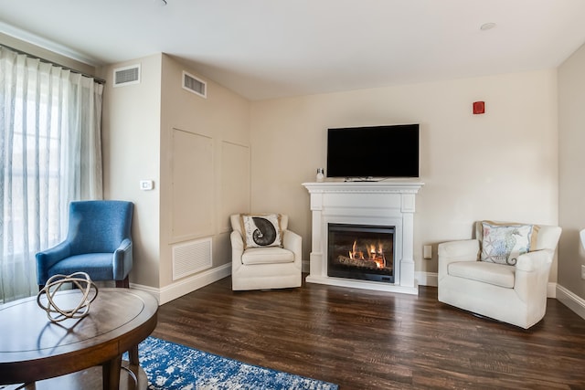 living area featuring a glass covered fireplace, wood finished floors, and visible vents