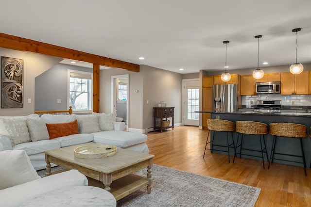 living room with recessed lighting, baseboard heating, light wood-type flooring, and baseboards
