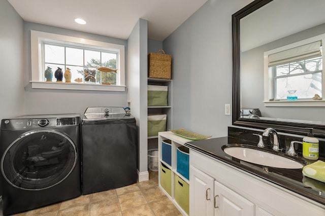 laundry area featuring washing machine and clothes dryer, a sink, and a wealth of natural light