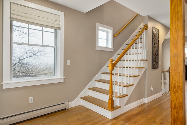 stairway with a baseboard radiator, wood finished floors, and baseboards