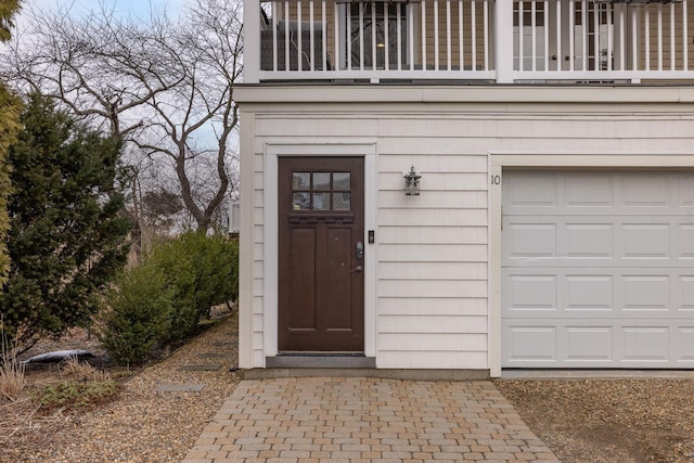 property entrance featuring an attached garage and a balcony