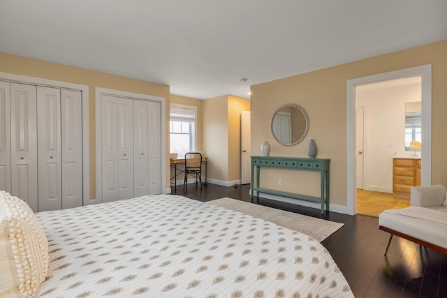 bedroom featuring dark wood-style flooring, baseboards, and two closets