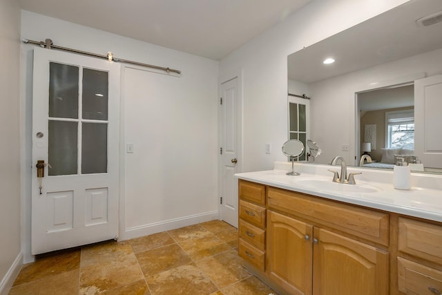 ensuite bathroom featuring vanity, baseboards, connected bathroom, visible vents, and stone finish flooring