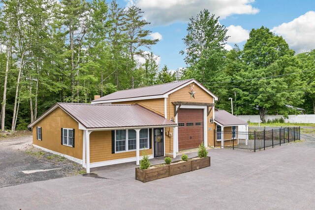 view of front of house featuring driveway, metal roof, a garage, and fence
