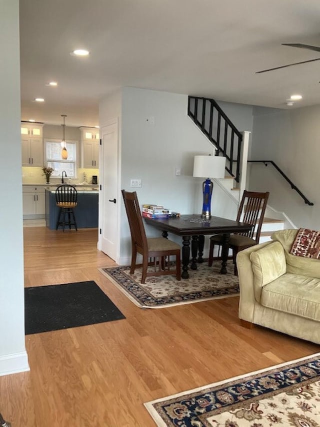 dining room with recessed lighting, baseboards, light wood finished floors, and stairs