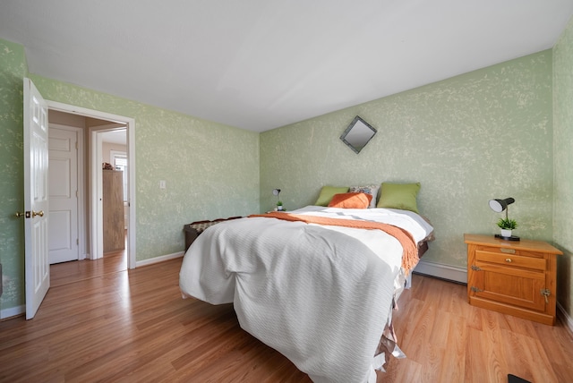 bedroom with baseboard heating, baseboards, and light wood-style floors