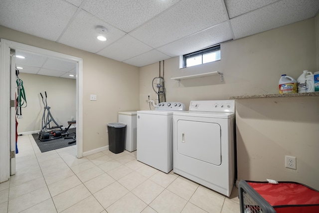 washroom with washing machine and clothes dryer, light tile patterned floors, laundry area, and baseboards