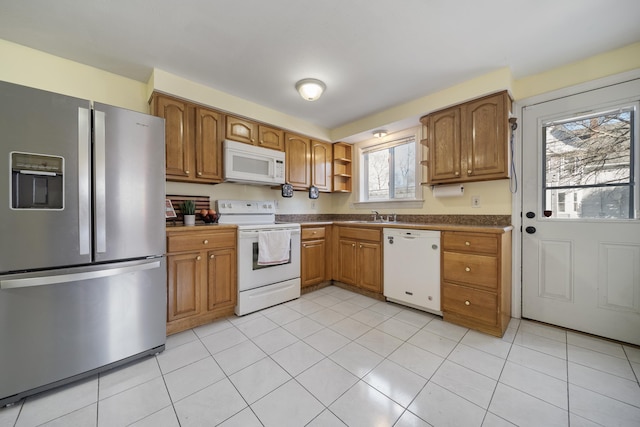 kitchen featuring dark countertops, open shelves, brown cabinetry, white appliances, and a sink