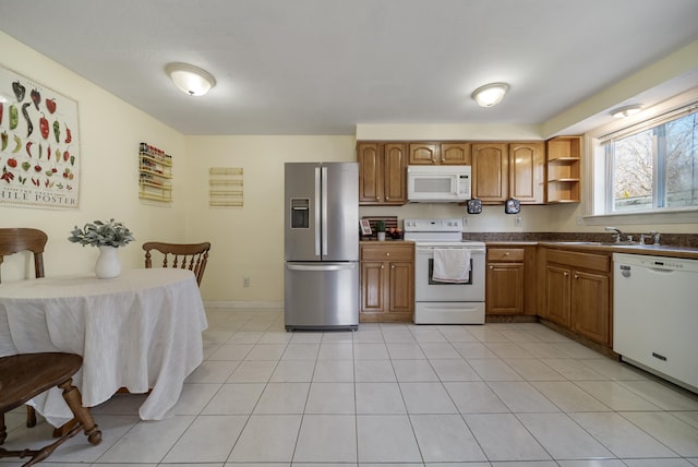 kitchen with dark countertops, brown cabinets, white appliances, and light tile patterned flooring