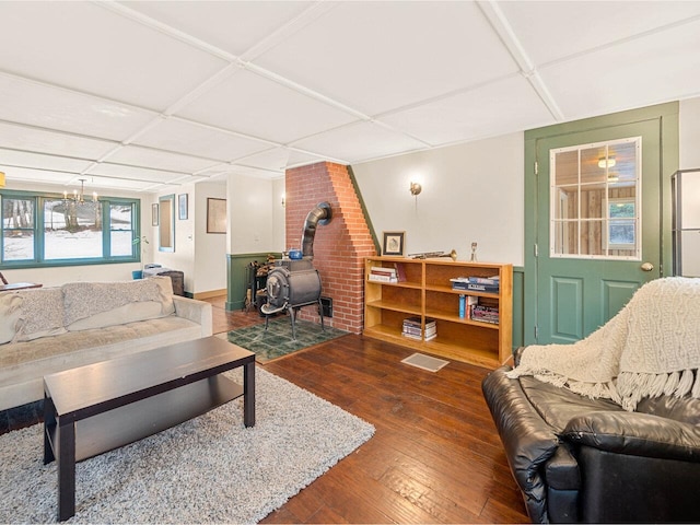 living room with a drop ceiling, hardwood / wood-style floors, and a wood stove