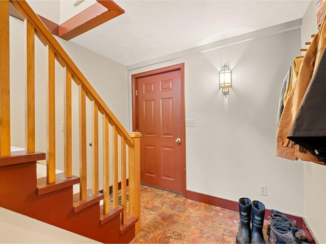entrance foyer with baseboards, stairs, and stone finish floor