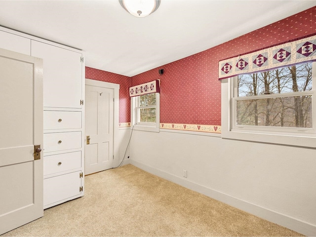 unfurnished bedroom with light colored carpet, wallpapered walls, and baseboards
