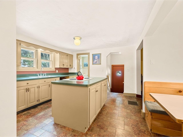 kitchen featuring a sink, visible vents, cream cabinetry, and stone finish flooring