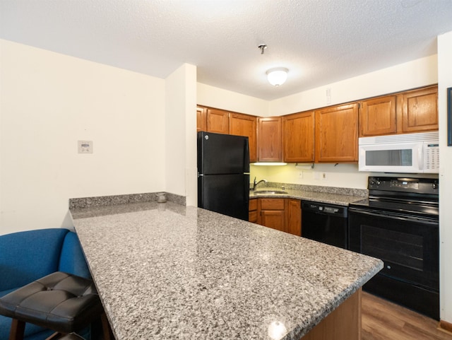 133 E Mountain Rd Unit 3C17, Killington, VT 05751 - kitchen with a sink, a kitchen breakfast bar, a peninsula, brown cabinetry, and black appliances