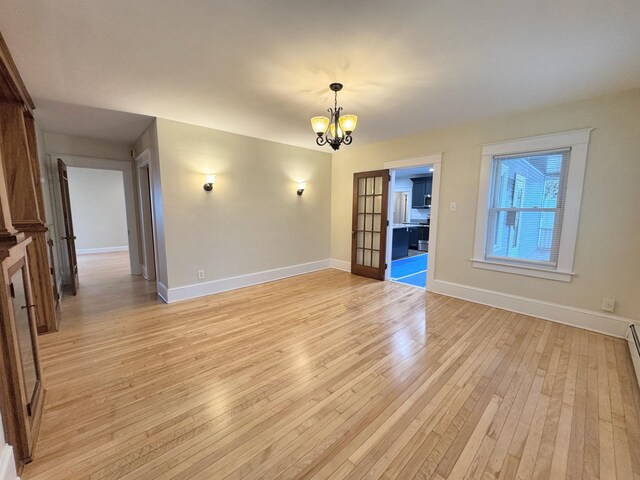 42 Elm St, Claremont, NH 03743 - unfurnished room with light wood-style floors, a chandelier, and baseboards
