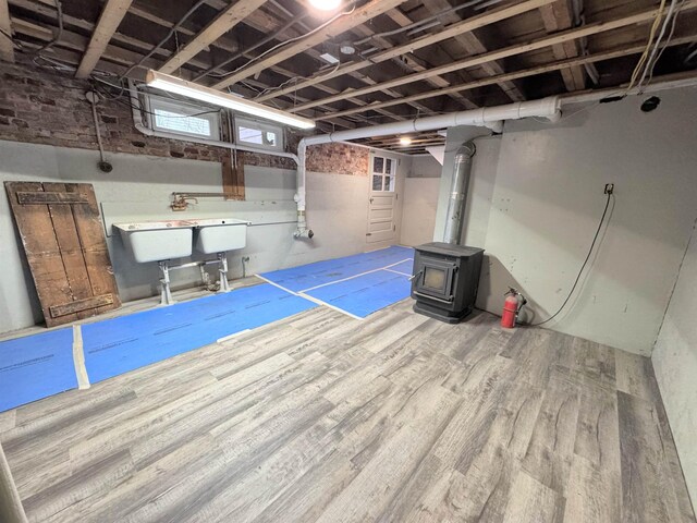 42 Elm St, Claremont, NH 03743 - basement featuring wood finished floors, a wood stove, and a sink
