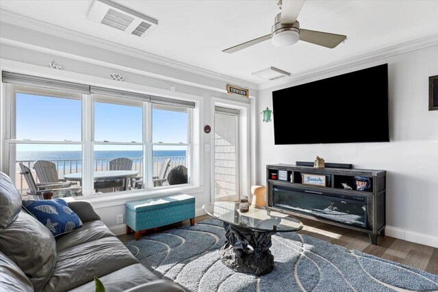 living area with crown molding, baseboards, ceiling fan, visible vents, and wood finished floors