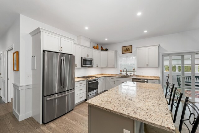 7 John Hardie Way, Chichester, NH 03234 - kitchen with appliances with stainless steel finishes, a sink, light wood-style floors, light stone counters, and a kitchen breakfast bar