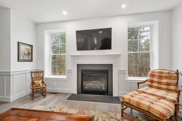 7 John Hardie Way, Chichester, NH 03234 - living area with a fireplace with flush hearth, wood finished floors, a healthy amount of sunlight, and wainscoting