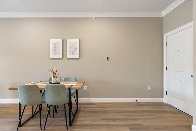 dining area with baseboards, ornamental molding, and wood finished floors