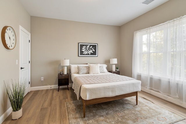 bedroom featuring baseboards, visible vents, and wood finished floors