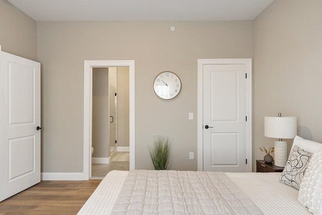 bedroom featuring baseboards, connected bathroom, and wood finished floors