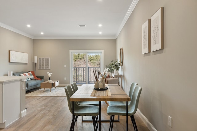 dining area with ornamental molding, baseboards, light wood finished floors, and visible vents