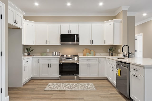 kitchen featuring ornamental molding, a sink, stainless steel appliances, and light wood-type flooring