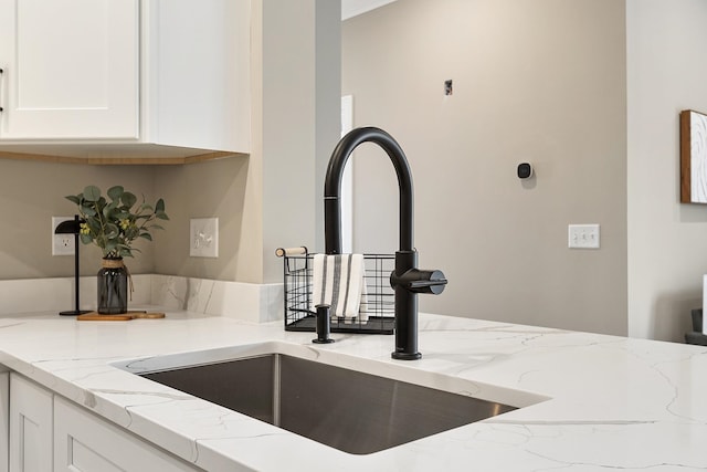 details featuring white cabinetry, a sink, and light stone countertops