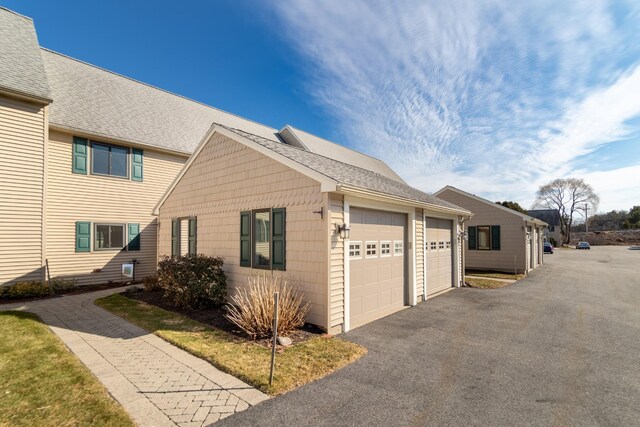 view of home's exterior with a garage and roof with shingles