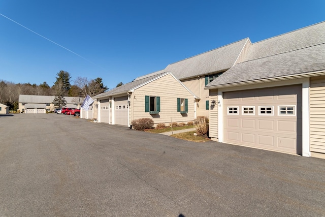 view of front of home featuring community garages and roof with shingles
