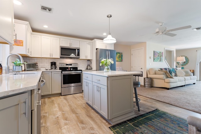 kitchen with decorative backsplash, visible vents, a kitchen bar, appliances with stainless steel finishes, and open floor plan