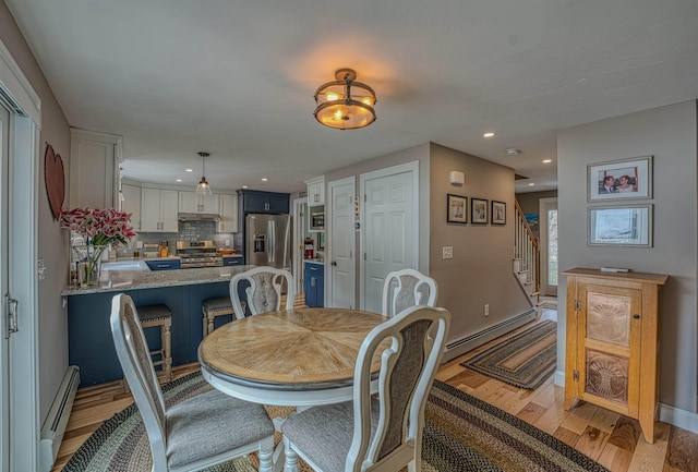 dining space featuring stairway, recessed lighting, a baseboard heating unit, and light wood-style floors